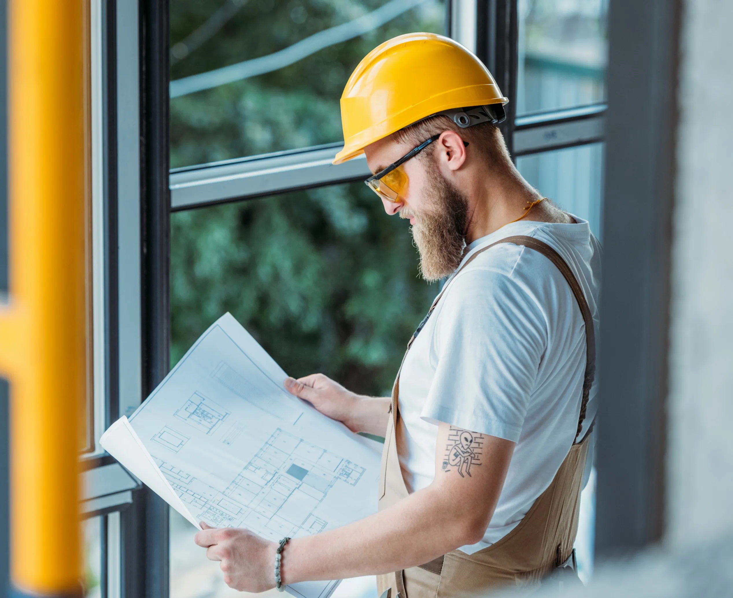 Contractor reviewing construction plans beside a window frame